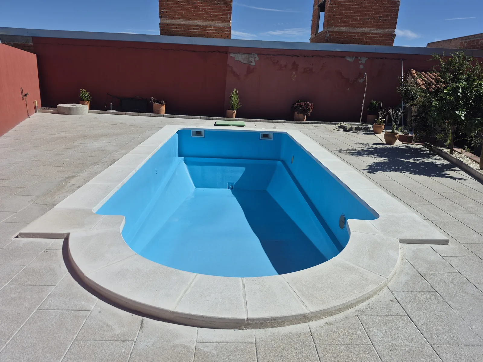 Piscina rehabilitada con forma curva y acabado azul claro