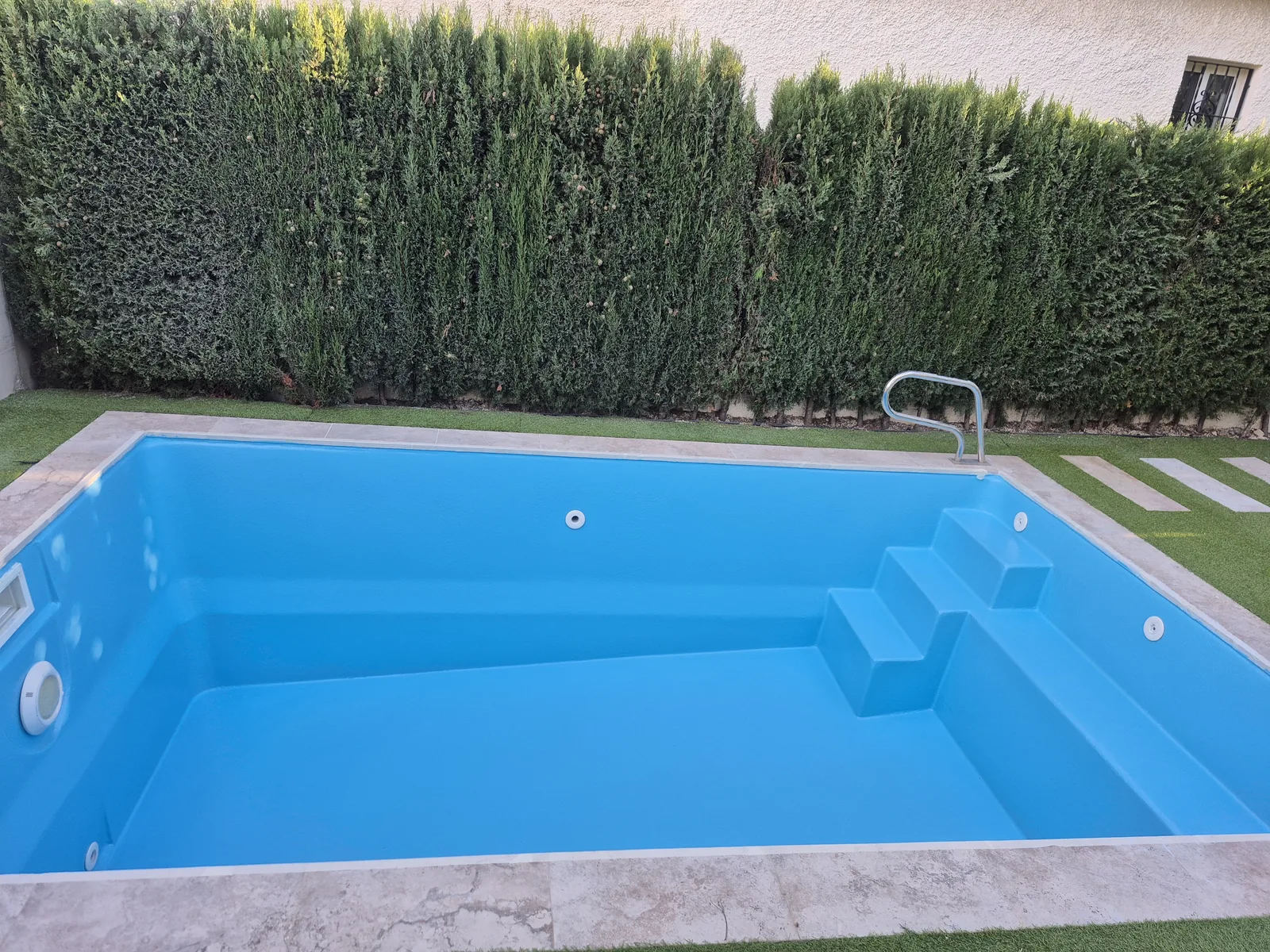 Piscina rectangular rehabilitada con acabado azul y escalera integrada