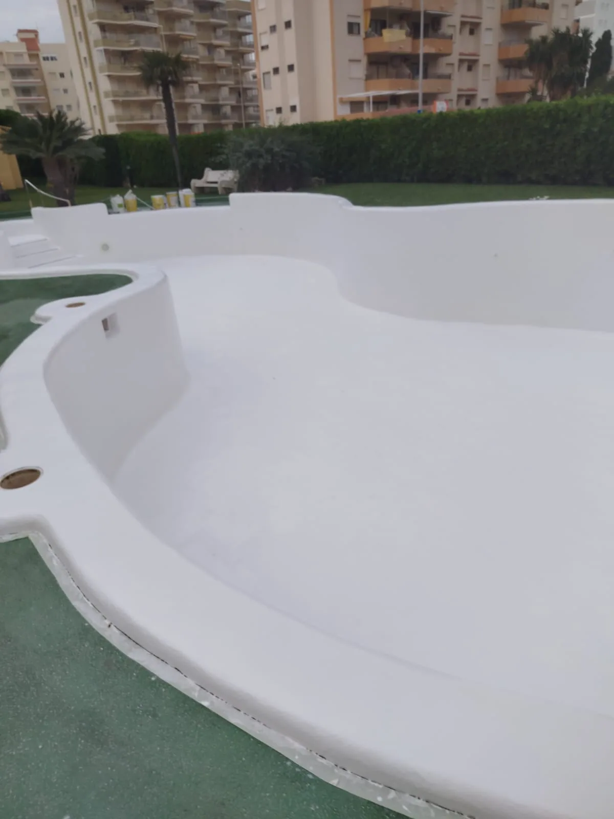 Piscina comunitaria de formas curvas con acabado blanco renovado en Xeraco